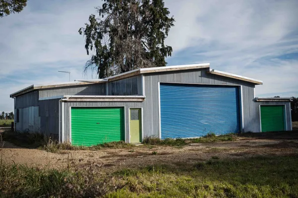 New multiple bay workshop shed with large roller doors and recycled iron walls to store machinery and implements