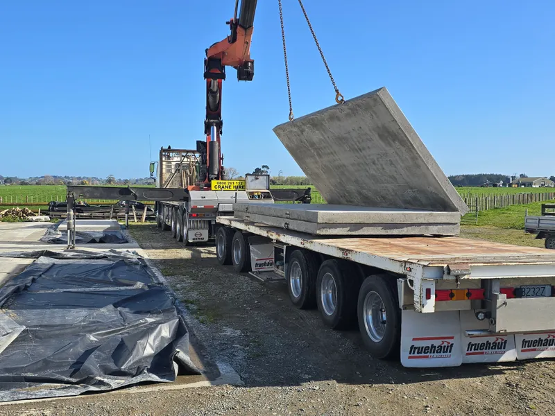 Crane lifting concrete planel off truck for agricultural concreting project