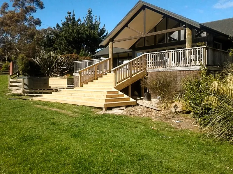 New staircase with railing and flared base of stairs to connect a upper level deck with the lawn