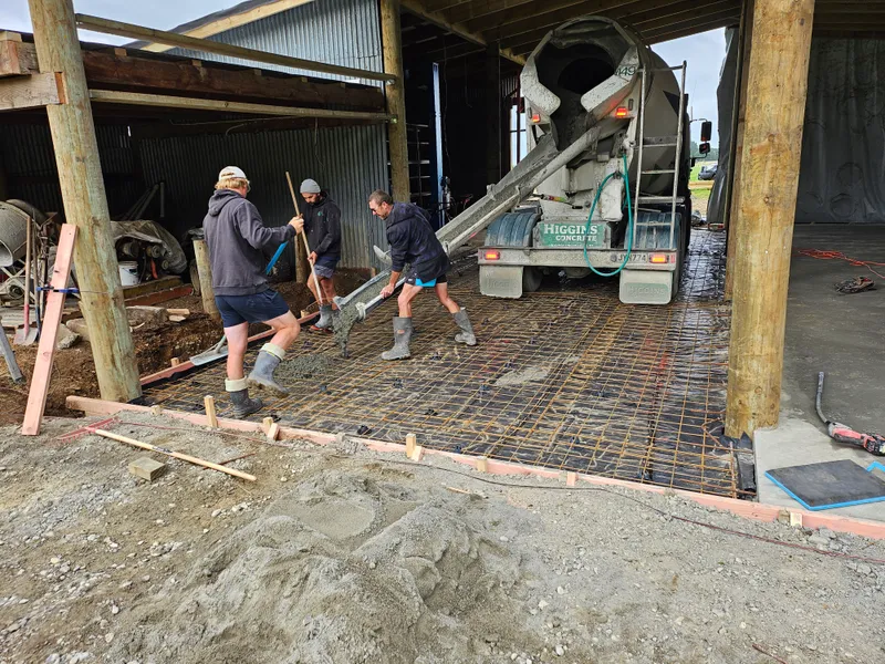 Construction workers pouring concrete for a concrete floor in a farm workshop