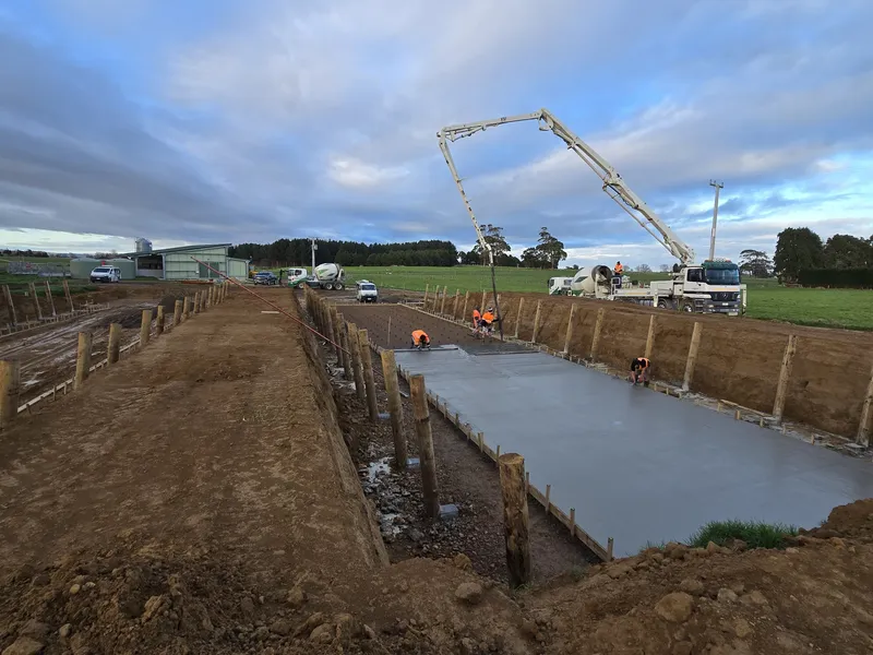 Concrete floor being poured by construction workers for silage bunker on dairy farm