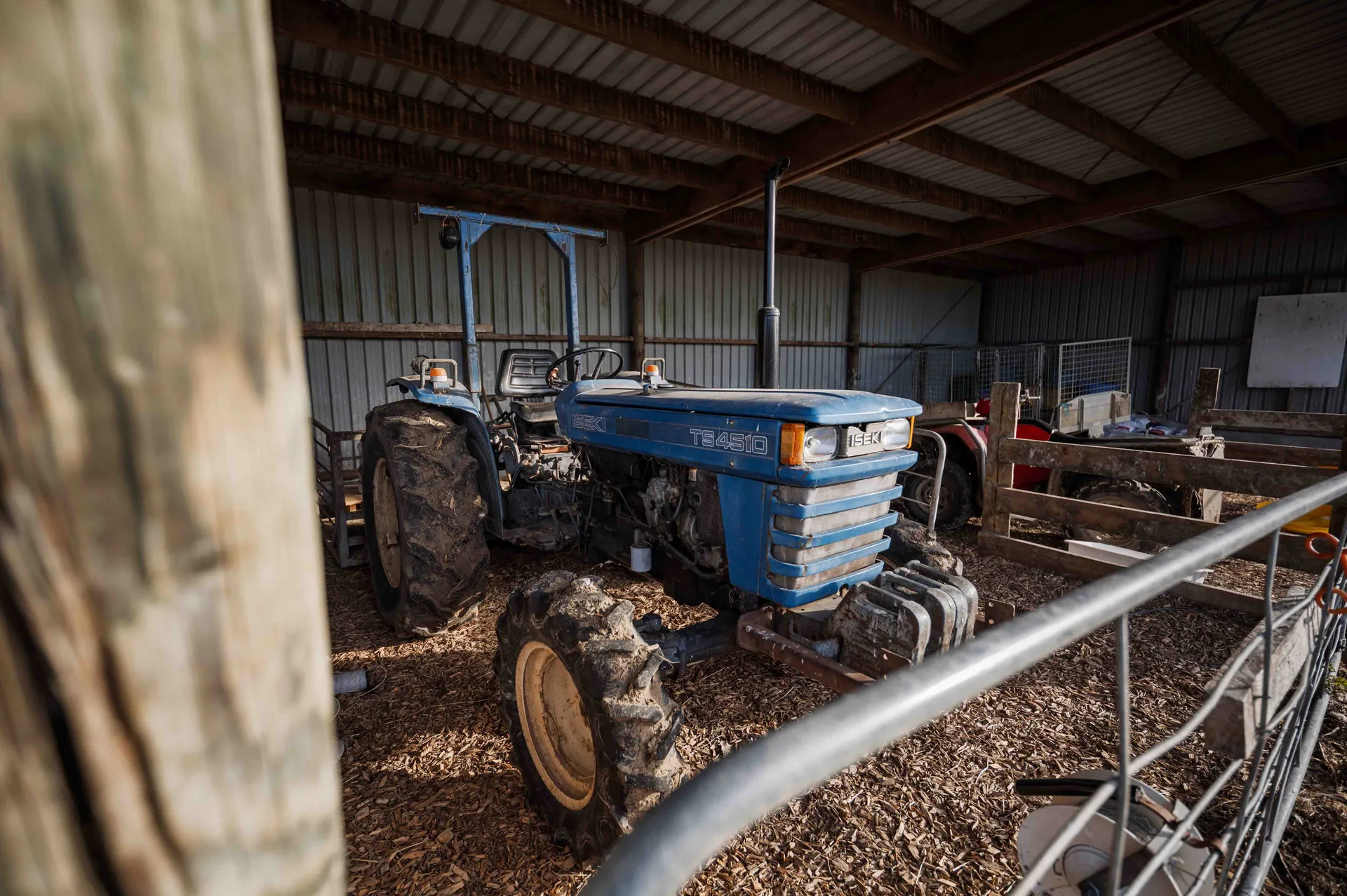 Blue tractor protected from weather in pole shed on farm