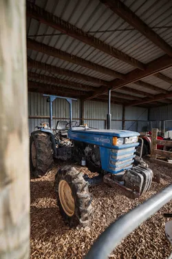 Blue tractor protected from weather in pole shed on farm